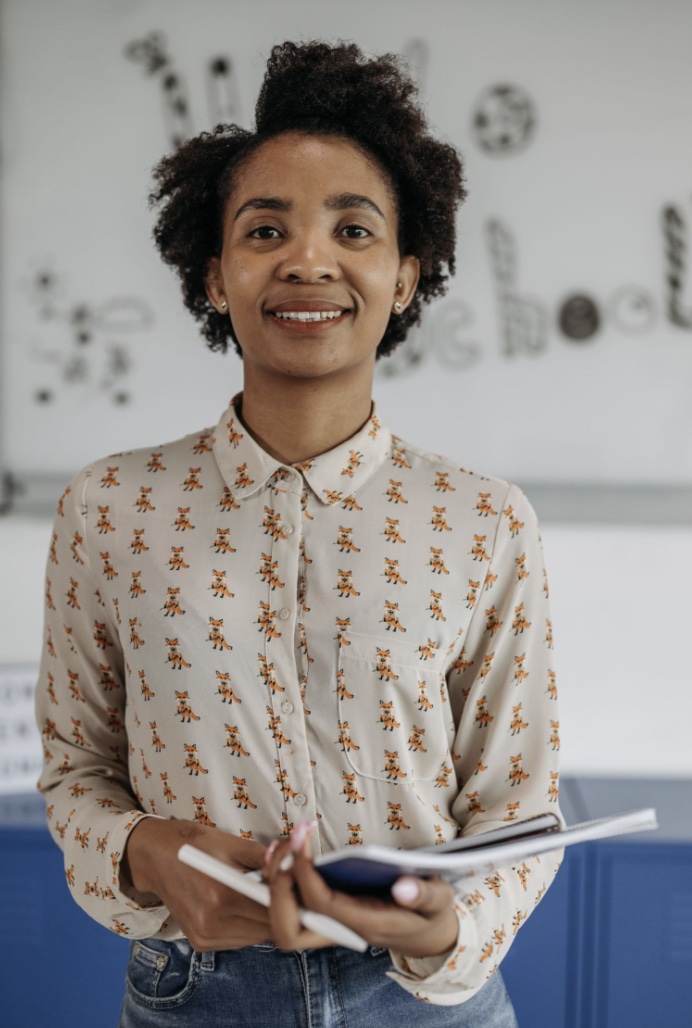 A confident educator holding a notebook in her classroom